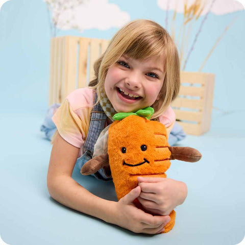 Girl holding a Warmies Carrot microwavable plush toy