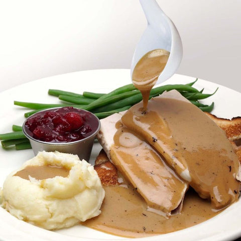 Porcelain Gravy Ladle 69/202 full of gravy being poured over plate of food