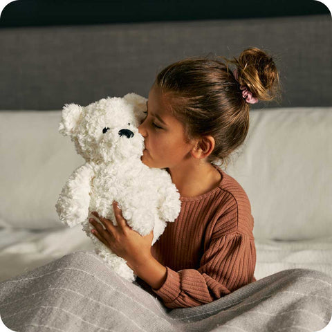 Girl holding a Warmies Cream Curly Bear microwavable Plush Toy