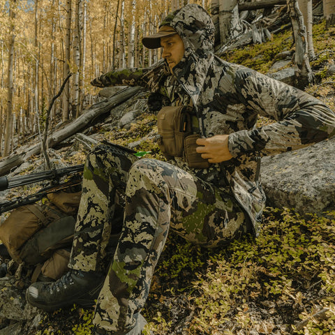 Hunter in woods wearing Pnuma men's Alpha Vertex camo pants